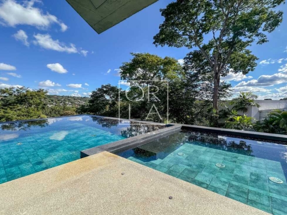 Piscina de borda infinita com revestimento em tons de verde e deck seco.