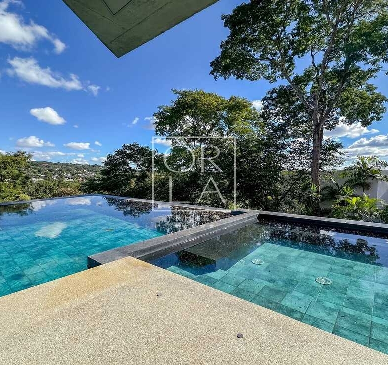 Piscina de borda infinita com revestimento em tons de verde e deck seco.