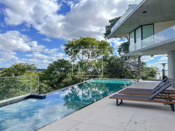 Piscina de borda infinita com vista para área verde e espreguiçadeiras.