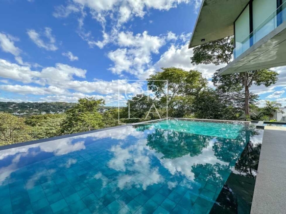 Piscina privativa com reflexo do céu e vegetação densa no Aldeia do Vale.
