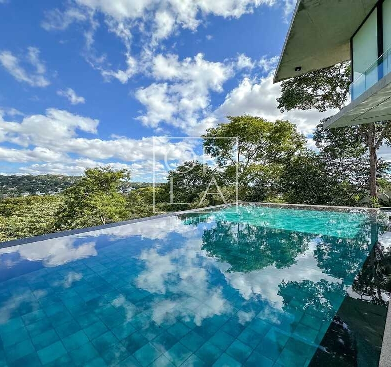 Piscina privativa com reflexo do céu e vegetação densa no Aldeia do Vale.