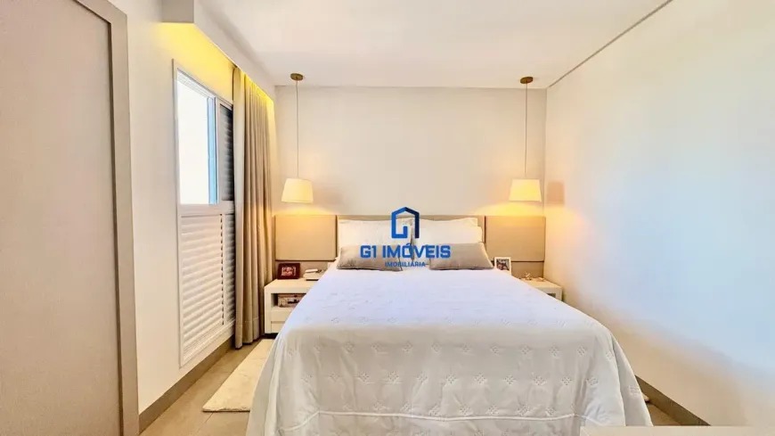 Quarto de casal com decoração clean, luminárias pendentes simétricas e cabeceira estofada em tons neutros.