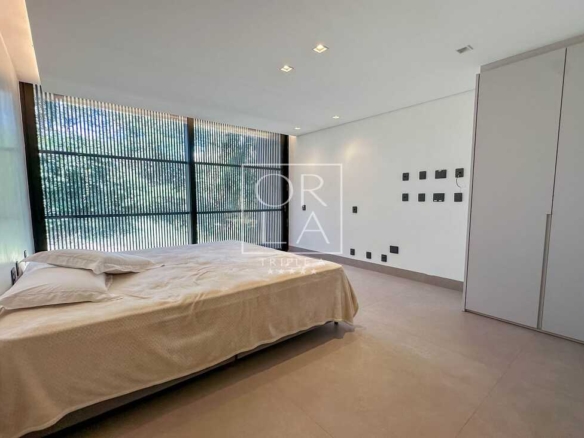 Quarto clean com cama de casal e vista para área verde no condomínio Aldeia do Vale.