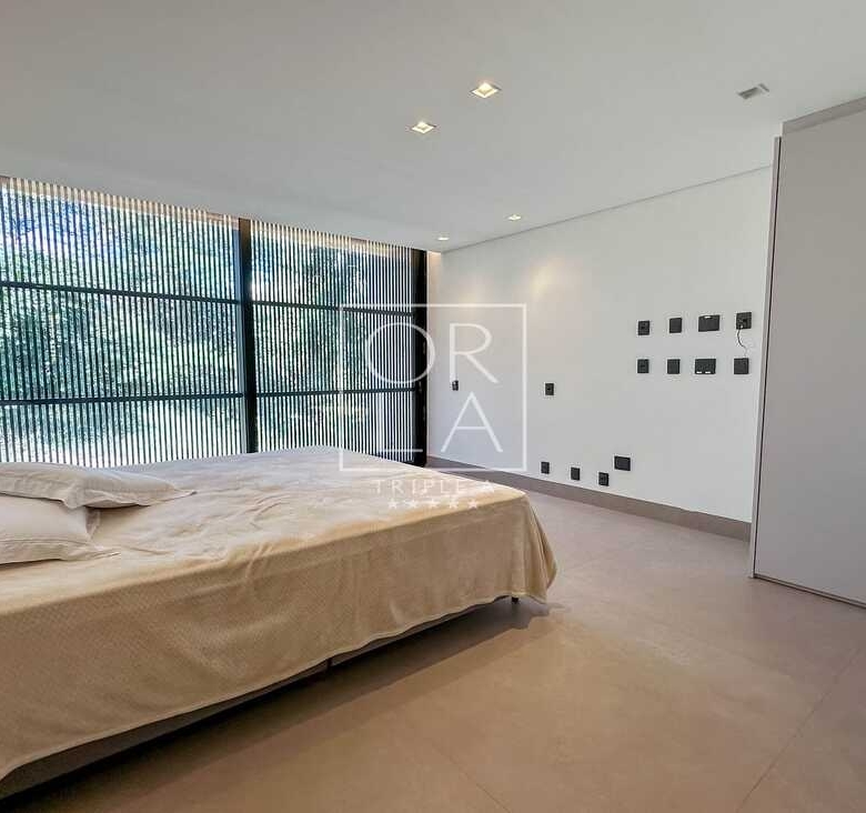 Quarto clean com cama de casal e vista para área verde no condomínio Aldeia do Vale.
