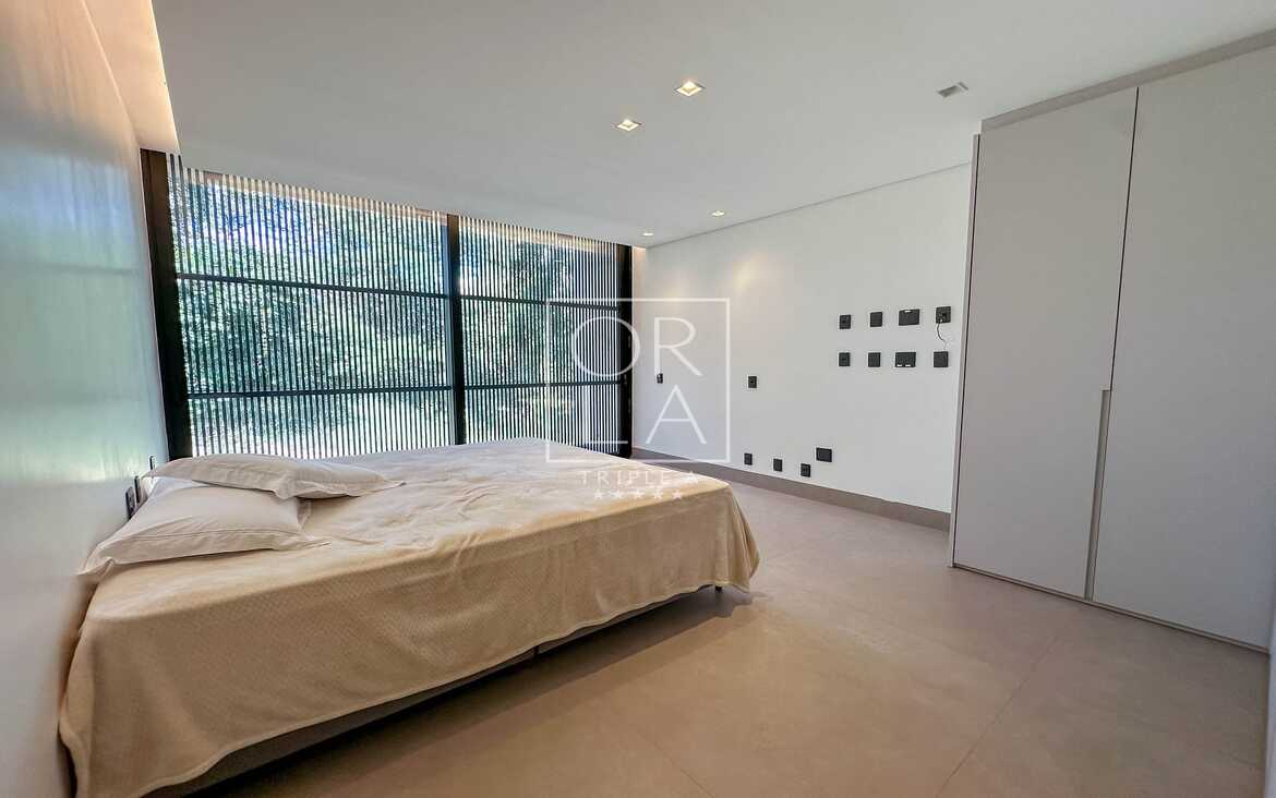 Quarto clean com cama de casal e vista para área verde no condomínio Aldeia do Vale.