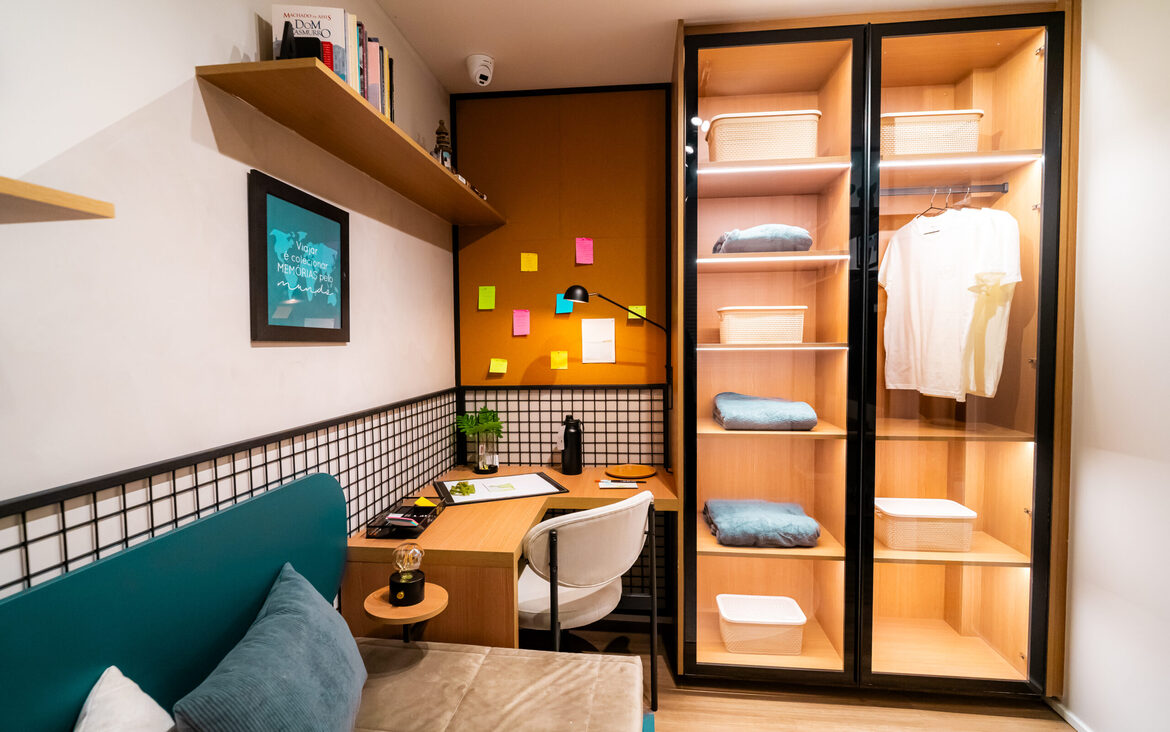 quarto-closet-office-iluminado Detalhe de home office no quarto com escrivaninha, mural de recados e closet com portas de vidro iluminadas.