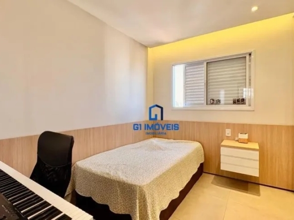 Quarto de solteiro ou escritório com cama, bancada de madeira e um teclado musical elétrico.