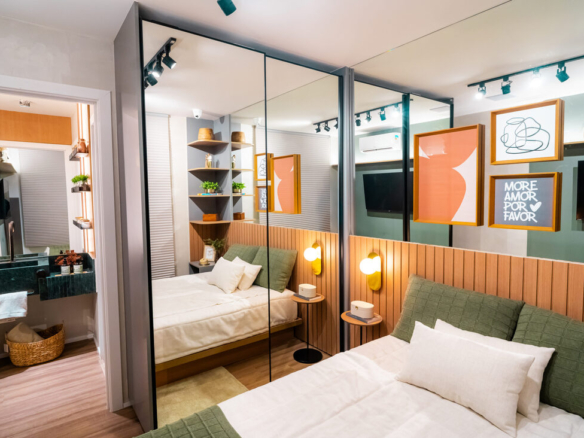 Quarto decorado no Now 111 com closet espelhado, cama com enxoval verde e cabeceira ripada em madeira.