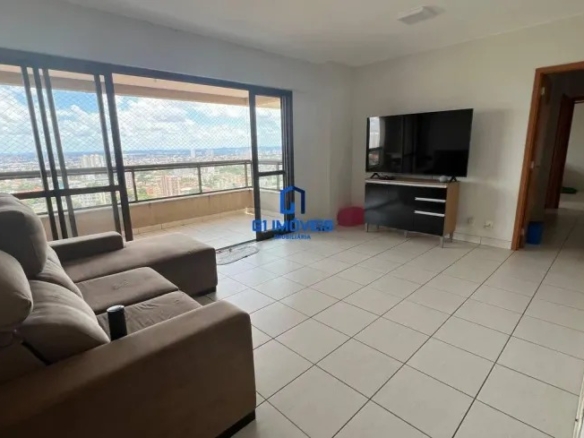 Sala de estar com sofá marrom, rack de TV e acesso à varanda em apartamento arejado.