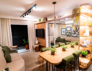 Sala de estar decorada com sofá bege, almofadas verdes e vista para a mesa de jantar e varanda.