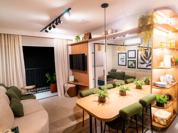 Sala de estar decorada com sofá bege, almofadas verdes e vista para a mesa de jantar e varanda.