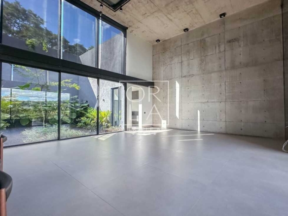 Sala de estar com pé direito duplo e amplas esquadrias de vidro para o jardim.