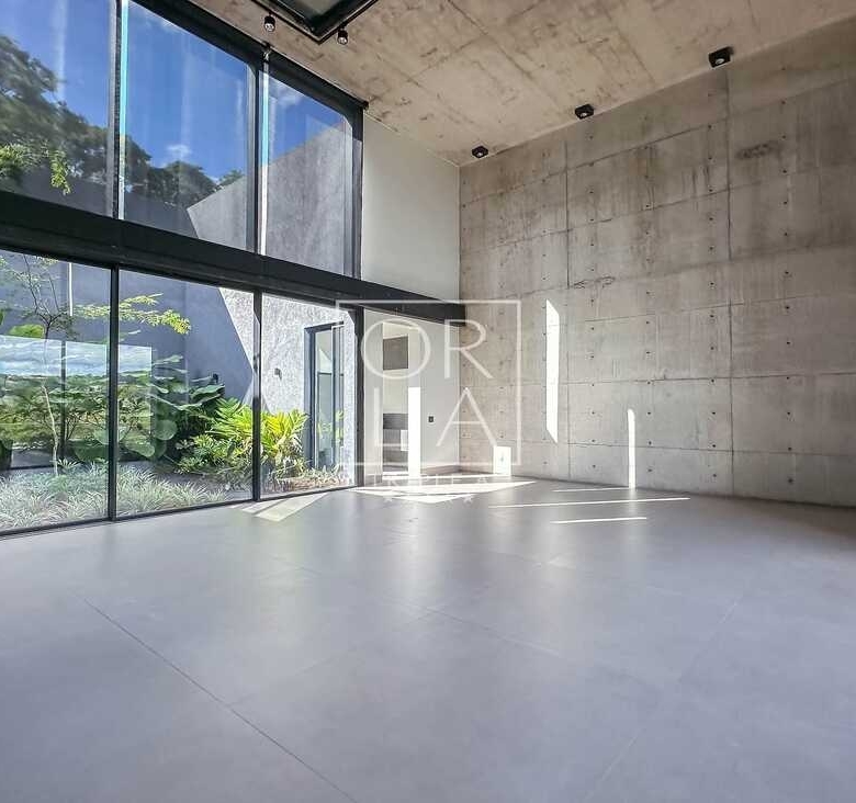 Sala de estar com pé direito duplo e amplas esquadrias de vidro para o jardim.