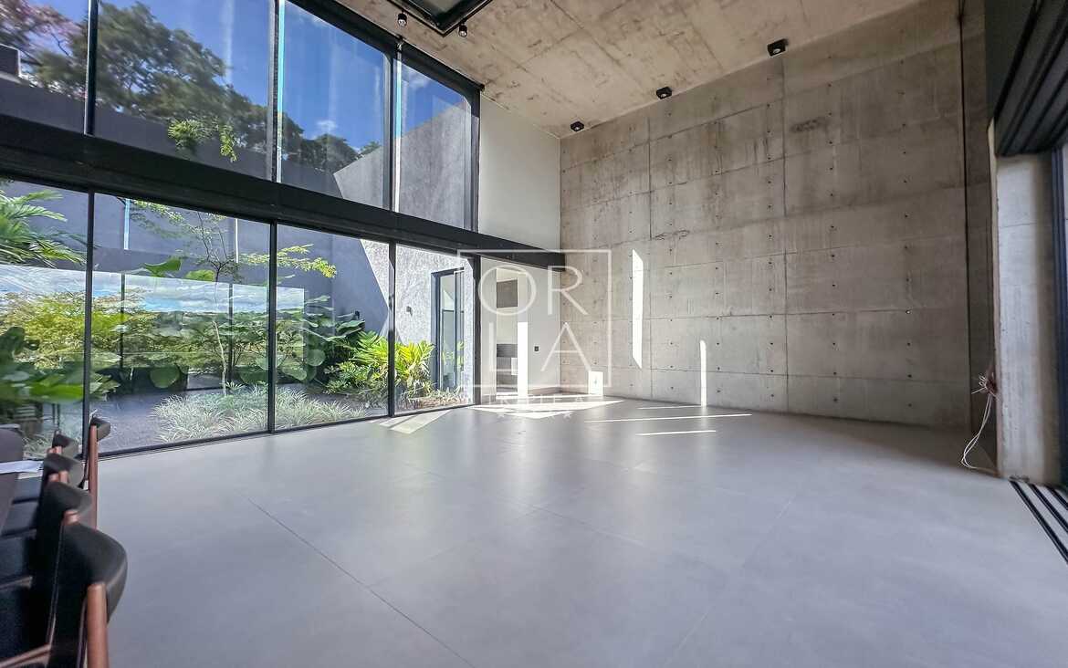 Sala de estar com pé direito duplo e amplas esquadrias de vidro para o jardim.