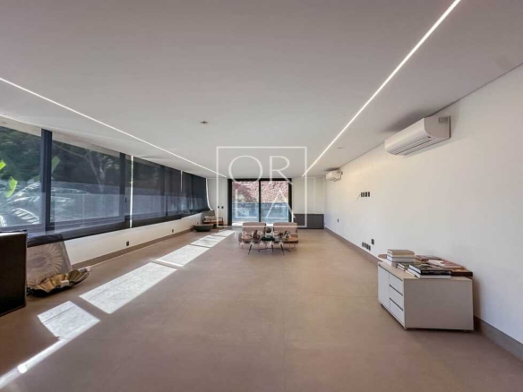 Corredor ou sala técnica extensa com iluminação de trilho e pé direito alto.