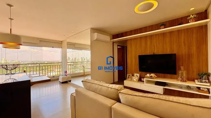 Sala de TV aconchegante com painel de madeira ripada, sofá bege e iluminação embutida no Residencial Auge.