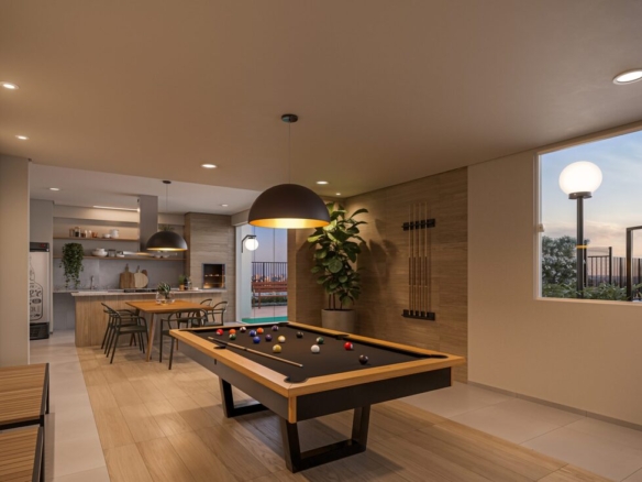 Salão de jogos com mesa de sinuca profissional, luminárias pretas e área gourmet ao fundo.