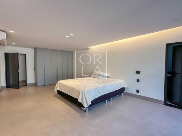 Suíte iluminada com acesso direto à varanda e grandes esquadrias pretas.