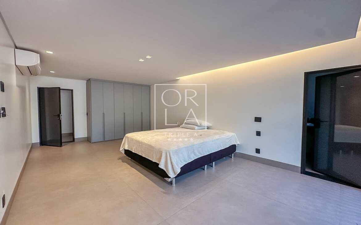 Suíte iluminada com acesso direto à varanda e grandes esquadrias pretas.