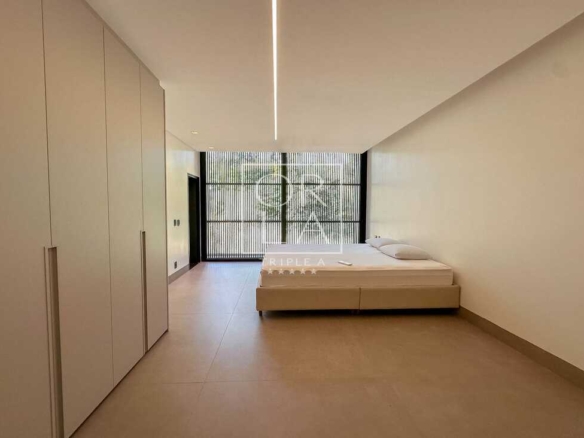 Suíte master com iluminação linear no teto, armários planejados e painel ripado no Aldeia do Vale.