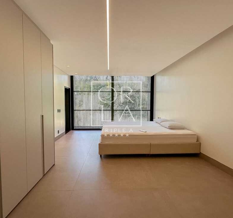 Suíte master com iluminação linear no teto, armários planejados e painel ripado no Aldeia do Vale.