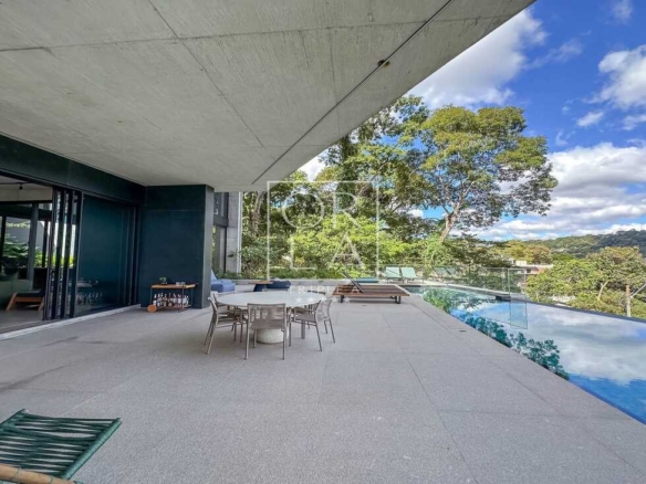 Varanda coberta com mesa de jantar externa e vista para a piscina.