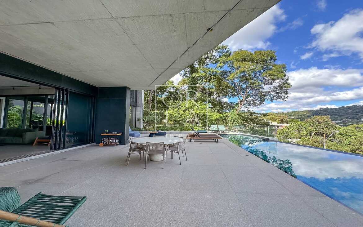 Varanda coberta com mesa de jantar externa e vista para a piscina.