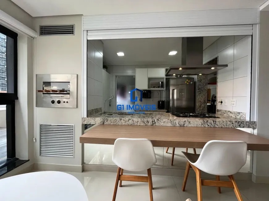 Varanda gourmet com churrasqueira integrada à cozinha no Maxxi 135.