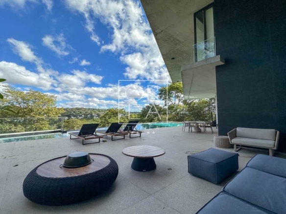 Varanda gourmet com sofás modernos e vista para o jardim suspenso.