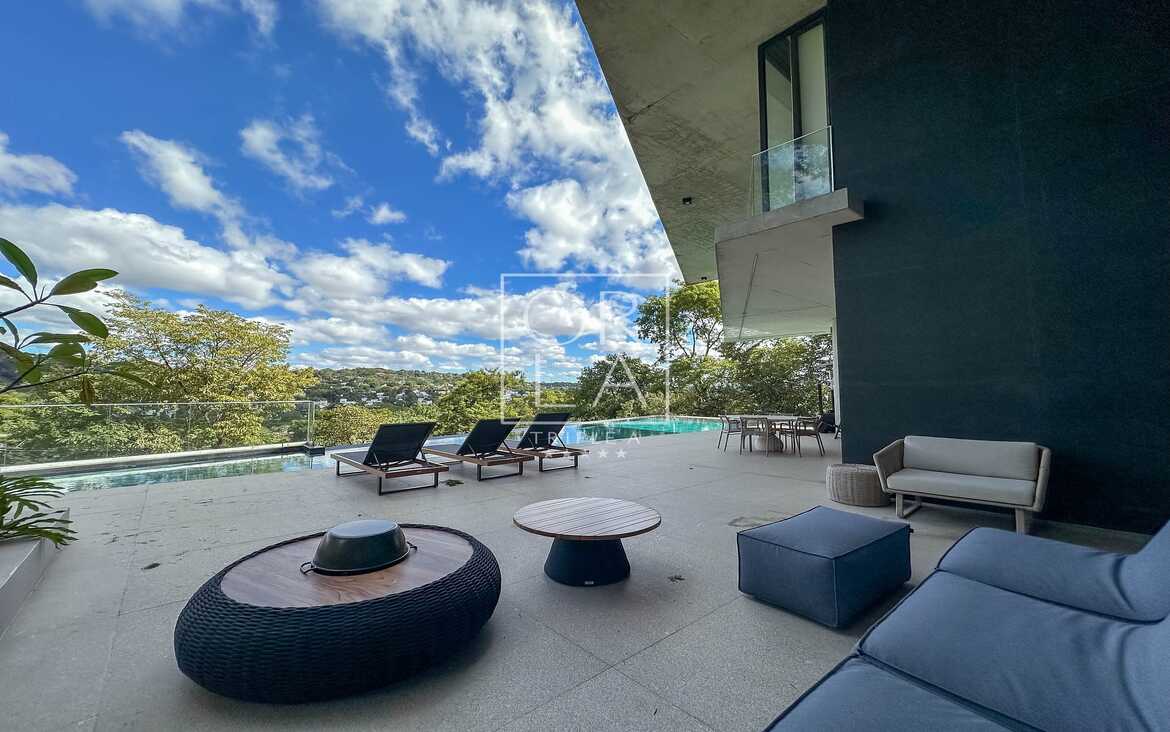 Varanda gourmet com sofás modernos e vista para o jardim suspenso.