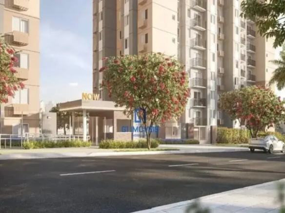 Fachada do residencial Now Milão com portaria moderna, torres altas e rua arborizada em dia de sol.