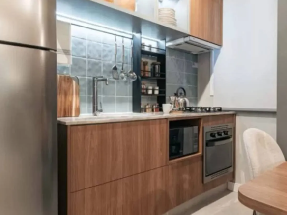 Cozinha planejada com armários de madeira, bancada clara e iluminação em LED em imóvel Now Praça C8 no Setor Sudoeste, Goiânia.