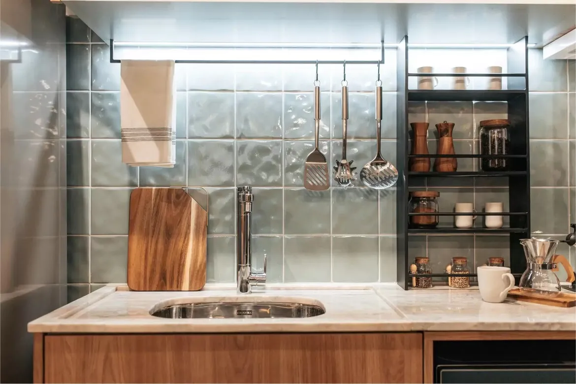 Detalhe da cozinha gourmet do Now Praça C8, com revestimento artesanal, bancada de pedra e marcenaria no Setor Sudoeste.