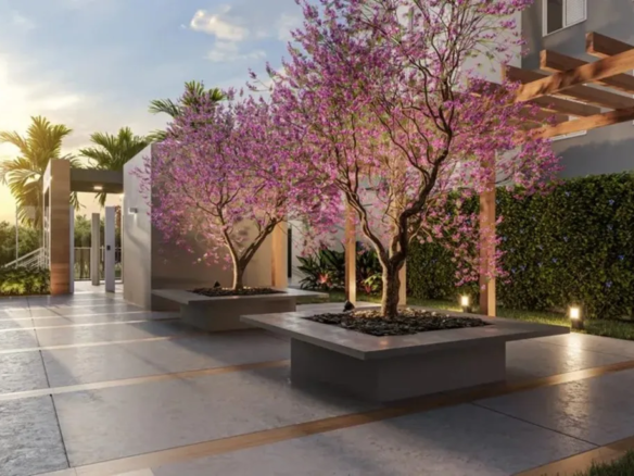 Área externa do Now praça C8 com paisagismo, árvores floridas e iluminação planejada ao entardecer, no Setor Sudoeste.