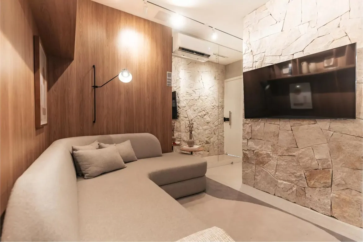 Sala de estar com painel de madeira e parede de pedra no apartamento decorado do Now Praça C8, Setor Sudoeste.