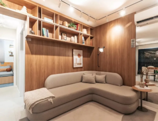 Sala de estar com estante embutida de madeira e sofá de design curvo no apartamento decorado do Now Praça C8, Setor Sudoeste.