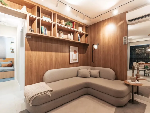 Sala de estar com estante embutida de madeira e sofá de design curvo no apartamento decorado do Now Praça C8, Setor Sudoeste.