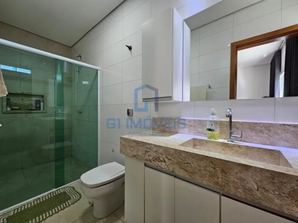 Banheiro da suíte com acabamento claro, box de vidro, nicho na parede e iluminação moderna.