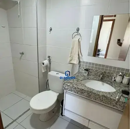 Banheiro social com pia em granito, espelho e revestimento claro no Condomínio Residencial You.