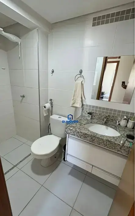Banheiro social com pia em granito, espelho e revestimento claro no Condomínio Residencial You.