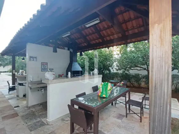 Quiosque gourmet com churrasqueira e mesas na área externa do Condomínio Residencial You.