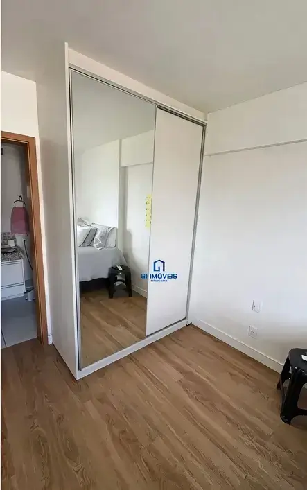 Quarto com guarda-roupa planejado branco e portas de espelho no Condomínio Residencial You.