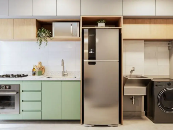 Cozinha planejada compacta com armários verdes, forno embutido e área de serviço integrada funcional.