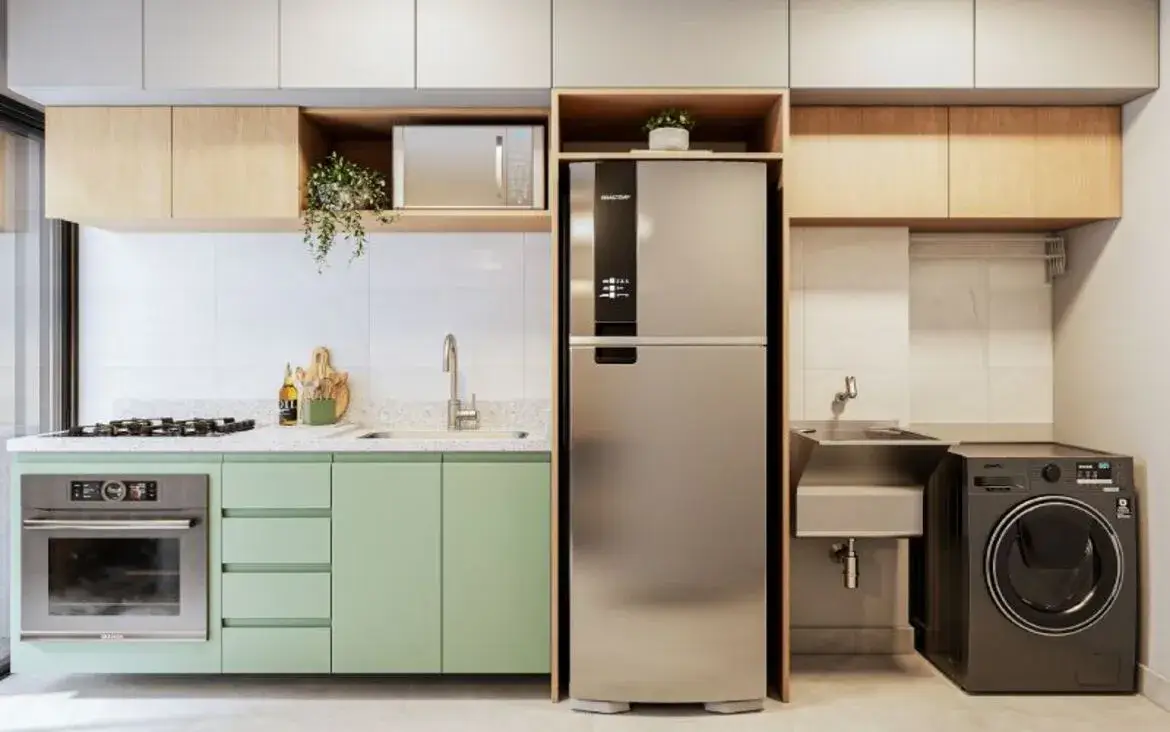 Cozinha planejada compacta com armários verdes, forno embutido e área de serviço integrada funcional.