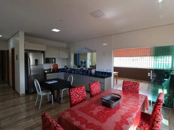 Cozinha residencial integrada à sala de jantar, com armários planejados e mesa com toalha vermelha.