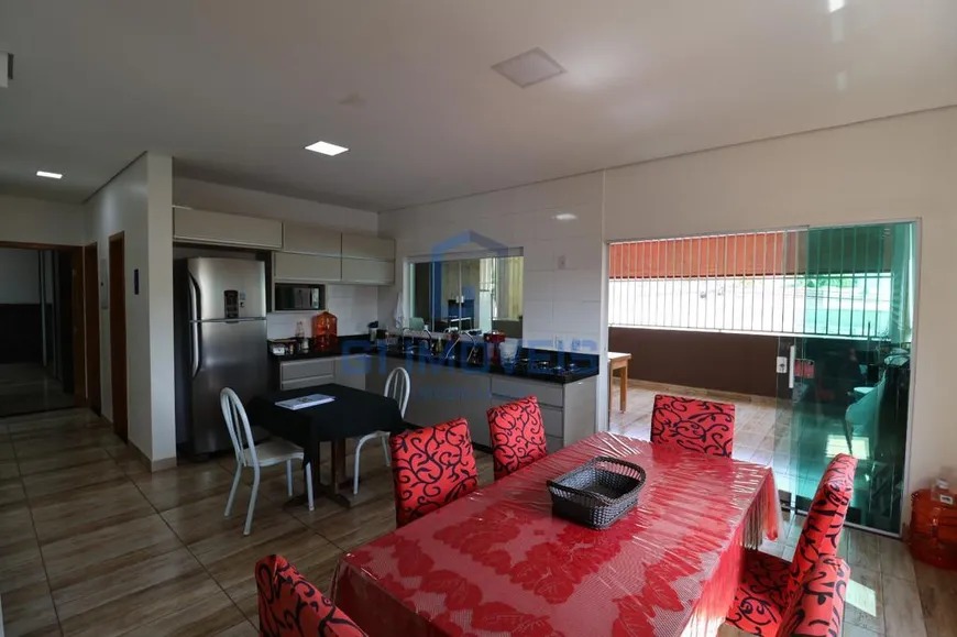 Cozinha residencial integrada à sala de jantar, com armários planejados e mesa com toalha vermelha.