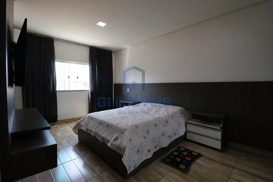 Quarto de casal espaçoso com cama box, cortinas escuras do teto ao chão e piso amadeirado.