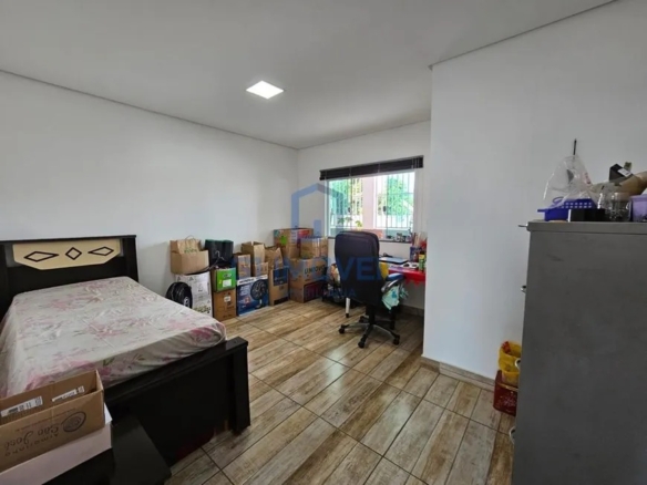 Quarto utilizado como home office com cama de solteiro, mesa de trabalho e caixas organizadoras.