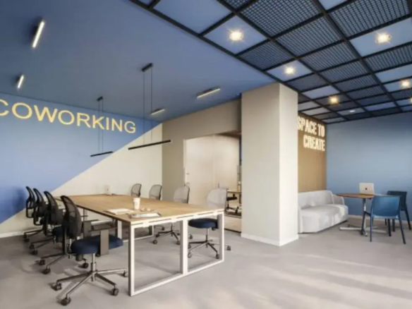 Sala de coworking moderna com mesas compartilhadas, design criativo e iluminação adequada para trabalho remoto.