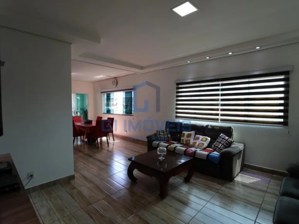 Sala de estar com sofá marrom, manta de crochê, mesa de centro e janela com persiana listrada.